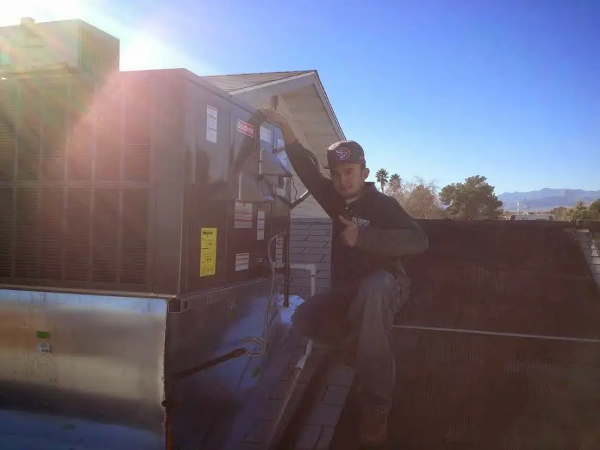 HVAC technician performing AC Tune-Up on a rooftop unit in Tiverton